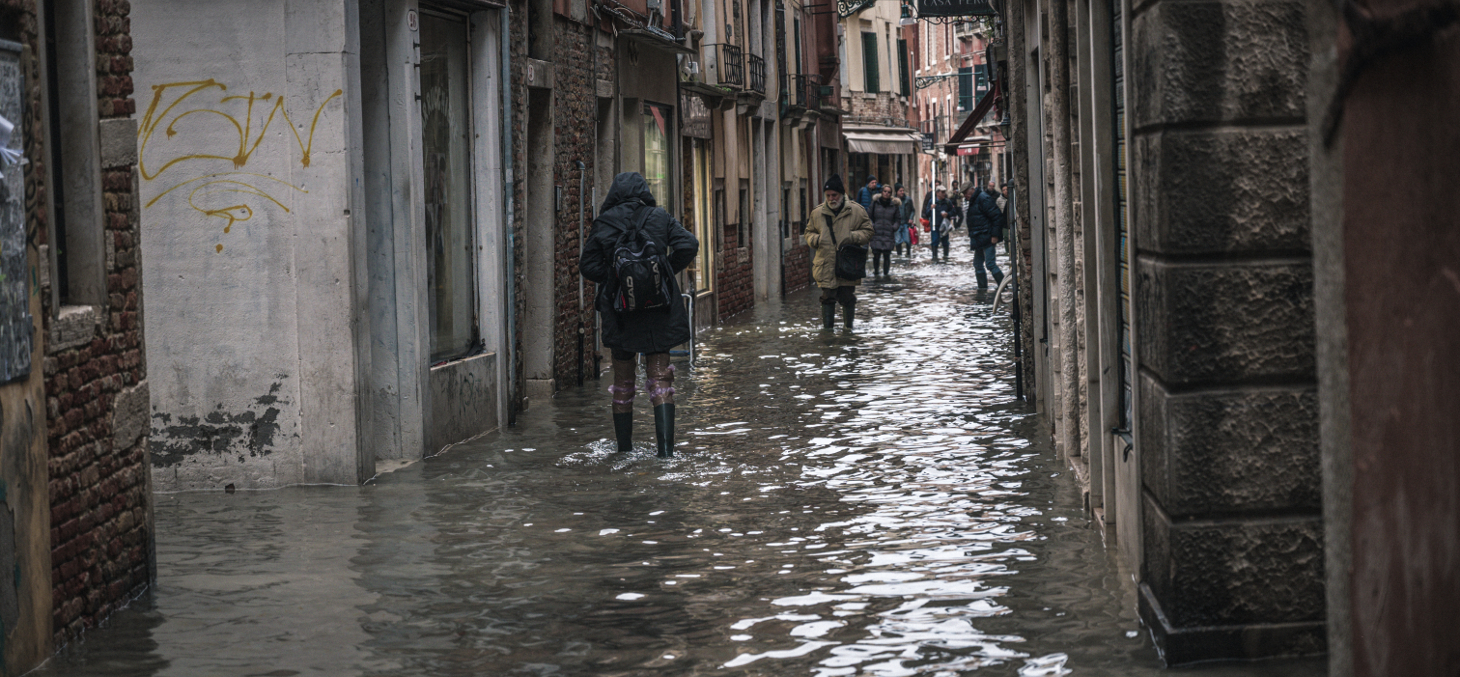 Venice, november 2019, locals and tourists endure the worst flood in more than 50 years in Venice lagoon. People pass the flooded streets of the city. Shutterstock